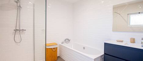 A modern bathroom with a shower, a bathtub, a vanity with a mirror, and a toilet.