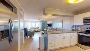 Una cocina moderna con electrodomésticos de acero inoxidable, una isla central con encimera de granito y armarios blancos.