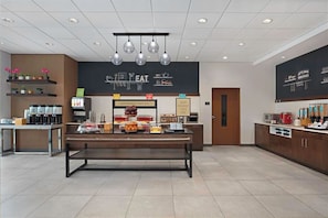 Ein stilvoller Frühstücksbereich mit einem Buffet, Kaffeeautomaten und einer Kreidetafel-Speisekarte.