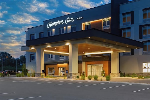 Ein Hampton Inn Hotel mit moderner Fassade, überdachter Eingang und Parkplatz.
