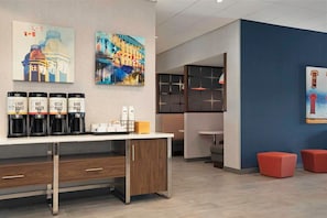 Eine moderne Hotelhalle mit Kaffee-Ecke, Kunstwerken an den Wänden und Sitzbereichen.