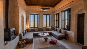 Una habitación acogedora con chimenea de piedra, techo de madera y ventanas amplias con vistas al desierto.