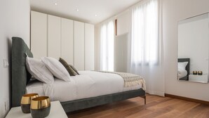 Ein modernes Schlafzimmer mit Bett, Nachttischen und einem großen Spiegel.