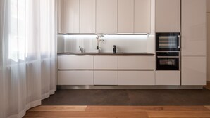 Eine moderne Küche mit weißen Schränken, einer Holz Arbeitsplatte und einem eingebauten Backofen.