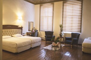 Una habitación de hotel con dos camas, una mesita, una silla y un radiador.