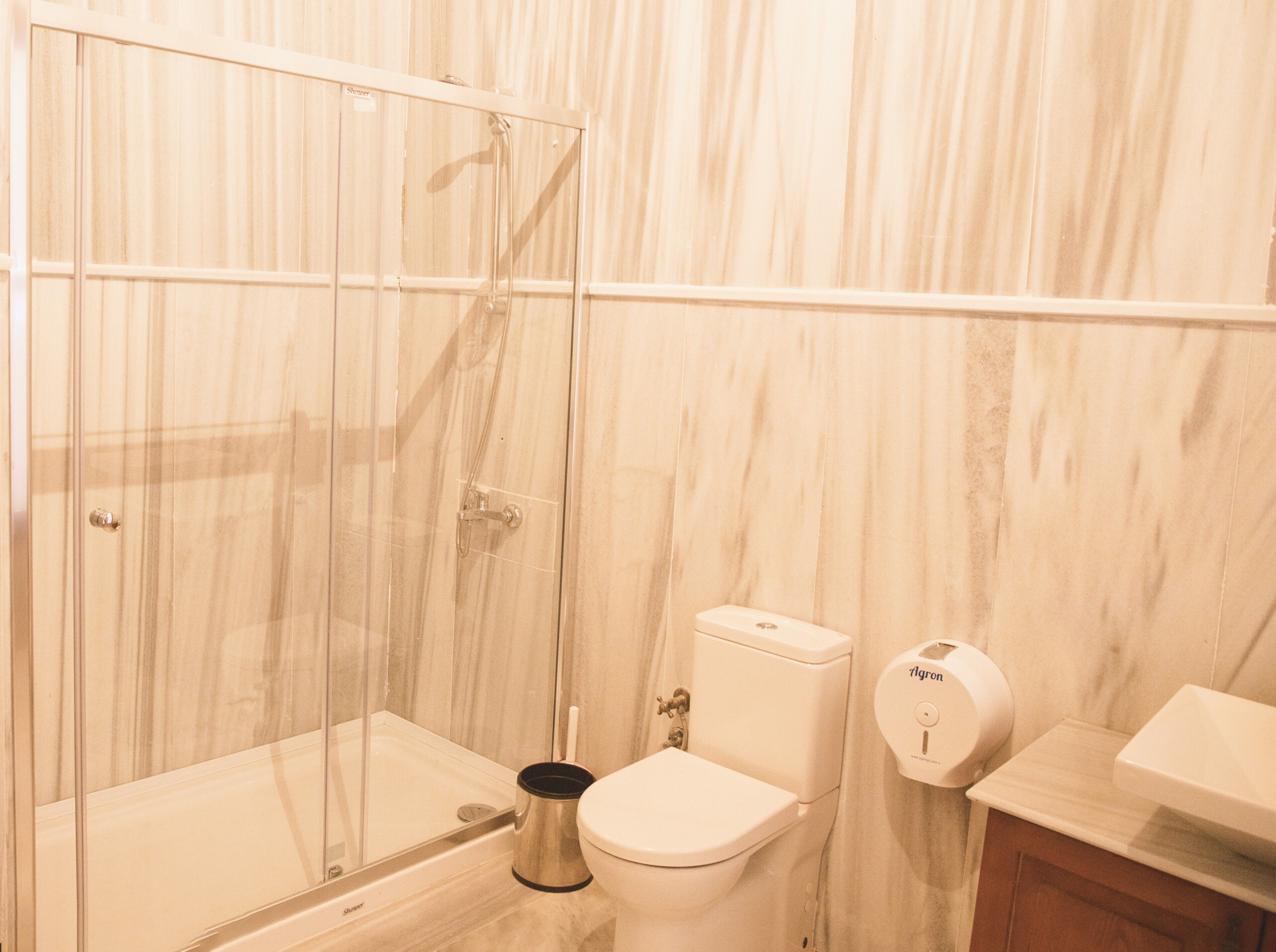 A bathroom with a glass-enclosed shower, a toilet, and a hand dryer.