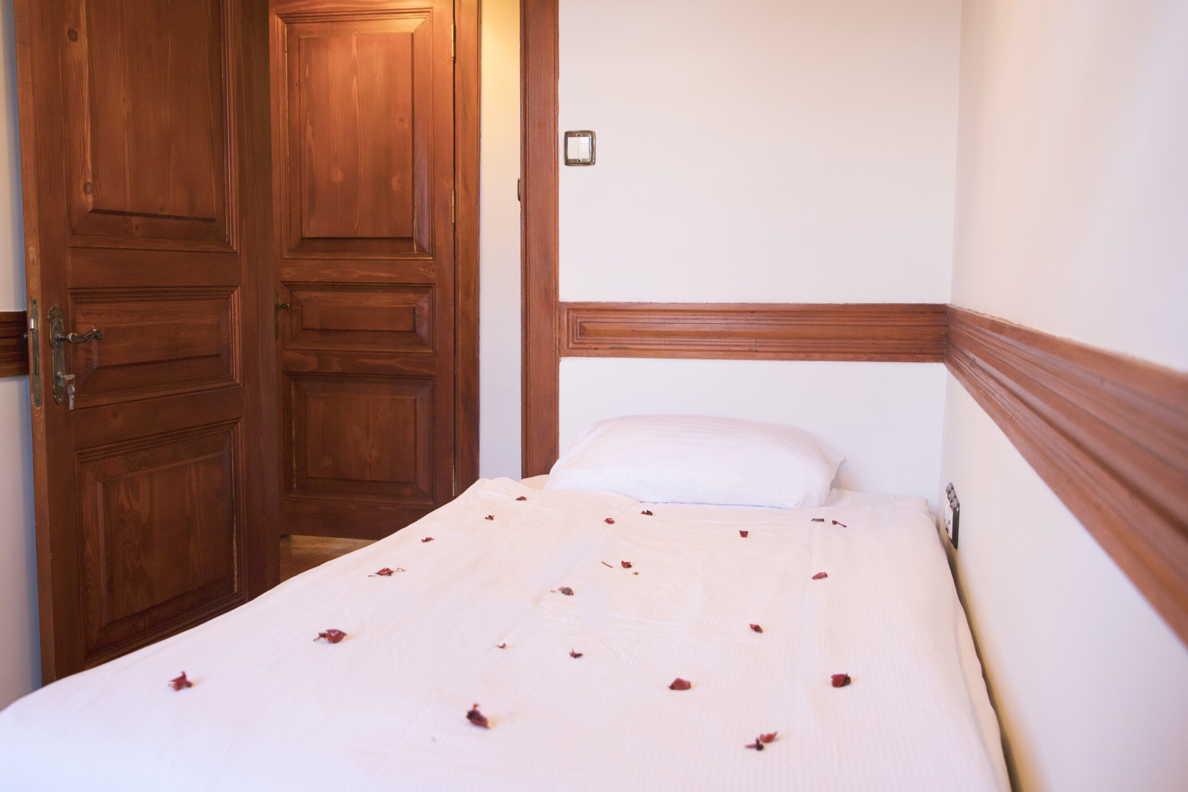 Un dormitorio con un armario de madera, una cama con cabecero blanco y un interruptor de luz en la pared.