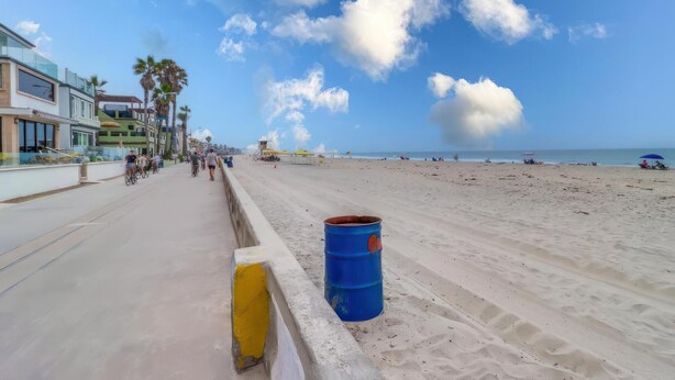 A beach with a blue barrel on the sand, a clear sky, and a few people in the distance. - Pismo Vacation Multi-Family Home (San Diego)