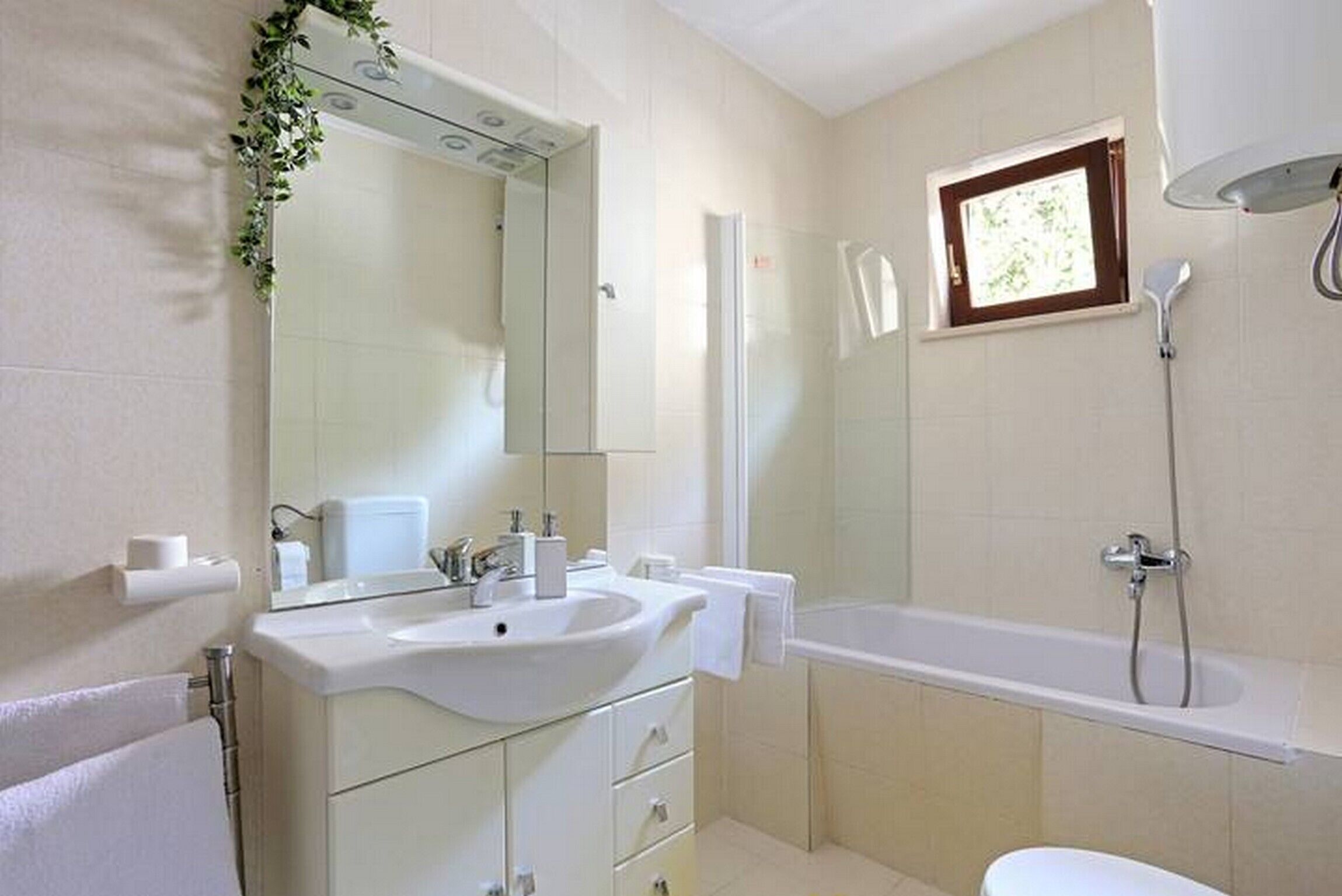 Un baño moderno con un lavamanos, espejo y bañera blancos.