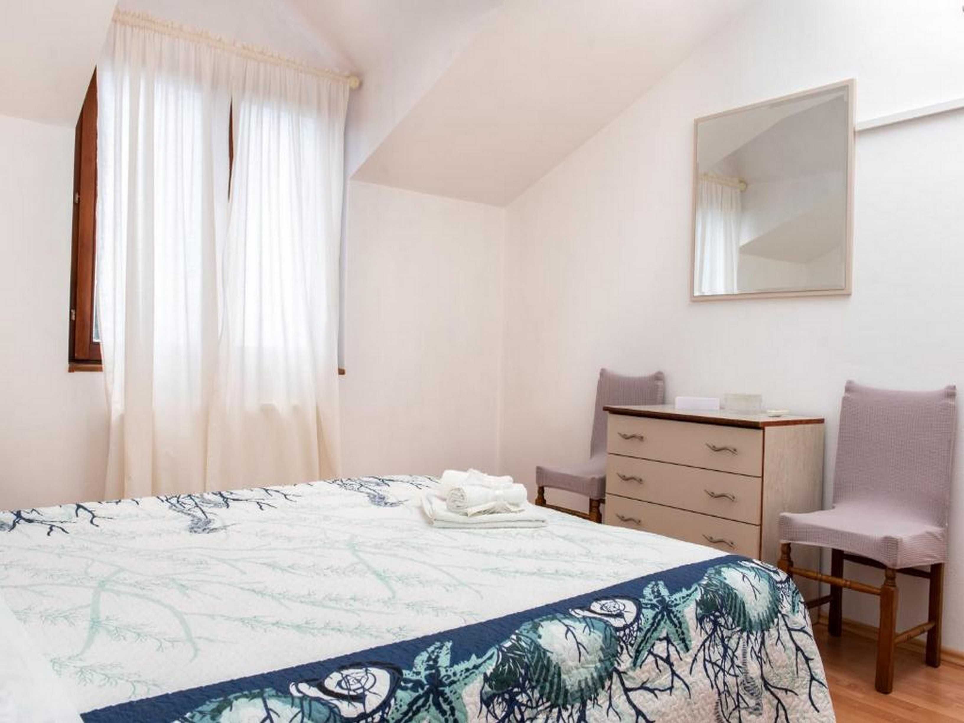 A bedroom with a bed, a dresser, a chair, and a mirror.