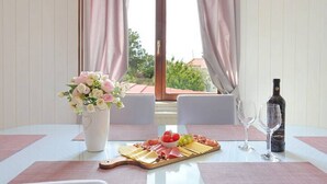 A dining table with a charcuterie board, a bottle of wine, and a vase of flowers. - Holiday Home Mons Aureus (Split)