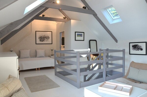 Une chambre de style « loft », avec un plafond en pente, un lit, un bureau et une lucarne.