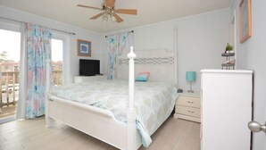 A bedroom with a four-poster bed, a ceiling fan, a television, a dresser, and a small plant. - 2-bedroom condo with an outdoor pool located uptown on the bayside in a peaceful, family-friendly neighborhood! (OCEAN CITY)