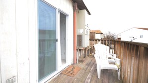 A wooden deck with a sliding glass door, a white chair, and a doormat. - 2-bedroom condo with an outdoor pool located uptown on the bayside in a peaceful, family-friendly neighborhood! (OCEAN CITY)