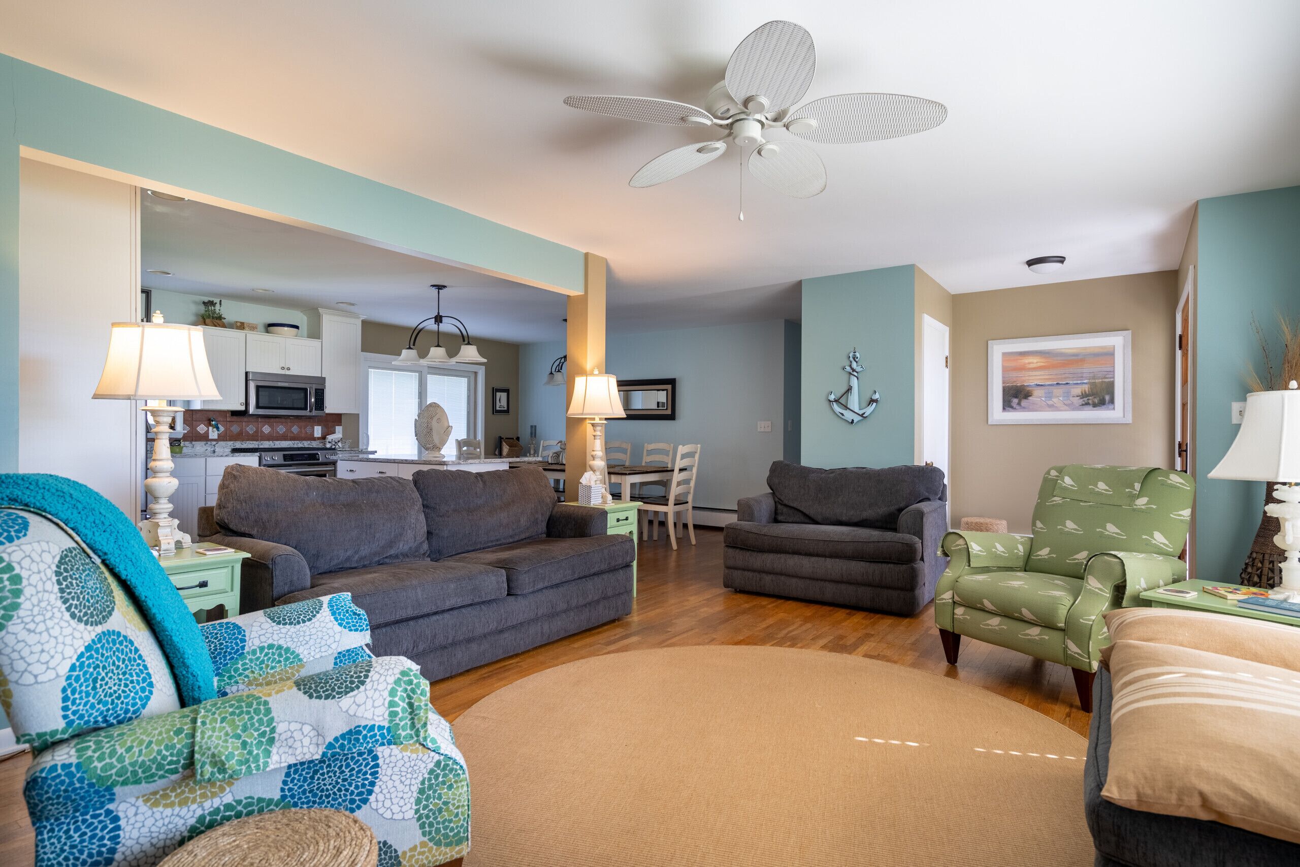A living room with a sofa, armchair, and a dining area with a table and chairs.