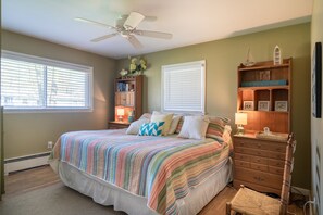 A bedroom with a bed, a ceiling fan, a bookshelf, a dresser, and a window with blinds. - Welcome to Anchors Away (South Haven)