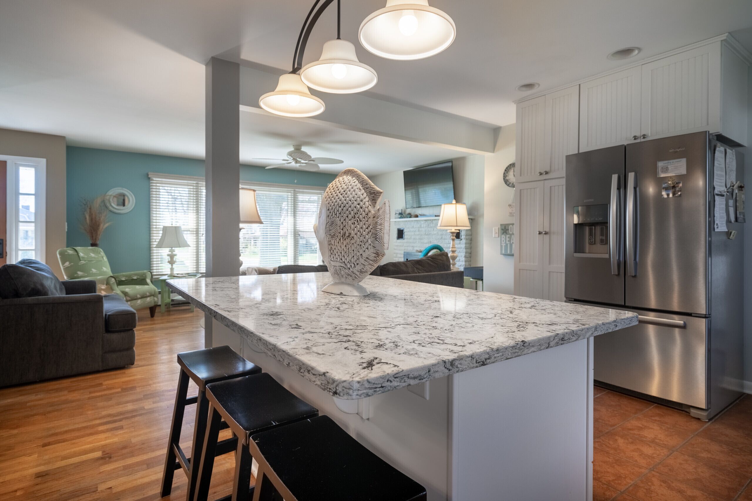 A modern kitchen with a central island, stainless steel appliances, and a seating area with a sofa and chairs.