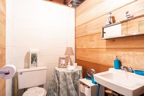 A small bathroom with a toilet, sink, and a small table with a mirror. - Welcome to Anchors Away (South Haven)