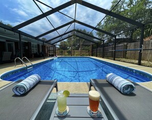 Relax by the pool under a shaded area, surrounded by lounge chairs and lush greenery.