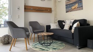 A modern living room with a black sofa, two grey armchairs, a round coffee table, and a wooden sideboard. - Vacation home under thatch on Usedom for 6 people with sauna and wood-burning stove, wall box. (Zirchow)
