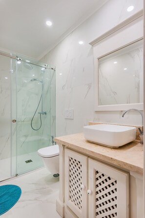 A modern bathroom with a glass-enclosed shower, a white sink, and a toilet. - 2BR at Chiado Historical Heart of Lisbon (Lisbon)
