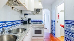 A kitchen with white cabinets, a double sink, a stove, and blue and white patterned tiles. - 2BR at Chiado Historical Heart of Lisbon (Lisbon)