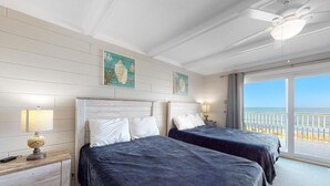 Ein Zimmer mit zwei Betten, einem Deckenventilator und Blick auf den Strand.