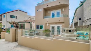 A modern building with a glass balcony, a sign for vacation rental, and a gated entrance. - Jamaica Palms & Penthouse, Sleeps 22 (San Diego)