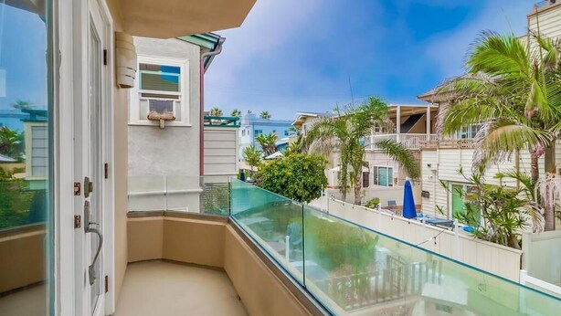 A balcony with a glass railing overlooking a residential area with palm trees and houses. - Jamaica Palms & Penthouse, Sleeps 22 (San Diego)
