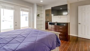 A bedroom with a bed, a dresser, a television, and a door. - Jamaica Palms & Penthouse, Sleeps 22 (San Diego)