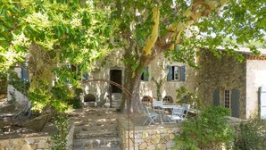 A stone building with a staircase leading to a patio area with outdoor furniture.