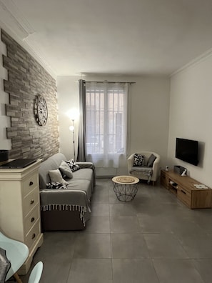 A modern living room with a sofa set, a coffee table, a TV, and a brick-patterned wall.