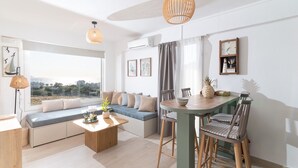 Una sala de estar moderna con un ventanal grande, un sofá, una mesa de comedor y una zona de cocina.