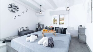 Un dormitorio moderno con una cama grande, una mesita de noche, un escritorio pequeño y una ventana con vistas.