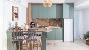 Una cocina moderna con una isla central, sillas de madera, una cafetera y una lámpara colgante.
