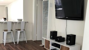 Una sala de estar moderna con un televisor de pantalla plana, un mueble blanco para entretenimiento y un aire acondicionado vertical.