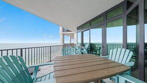 Un balcon avec une table et des chaises en bois, donnant sur la mer.