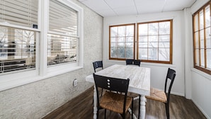 A dining room with a wooden table and four chairs, large windows with blinds, and a textured wall. - 1 Block to Allianz Field • Sleeps 8+ • Patio & Parking (Saint Paul)