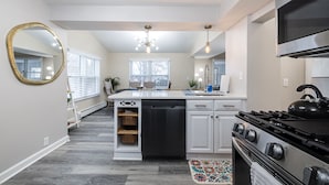 A modern kitchen with white cabinetry, a black stove, and a large island with a dishwasher. - 1 Block to Allianz Field • Sleeps 8+ • Patio & Parking (Saint Paul)