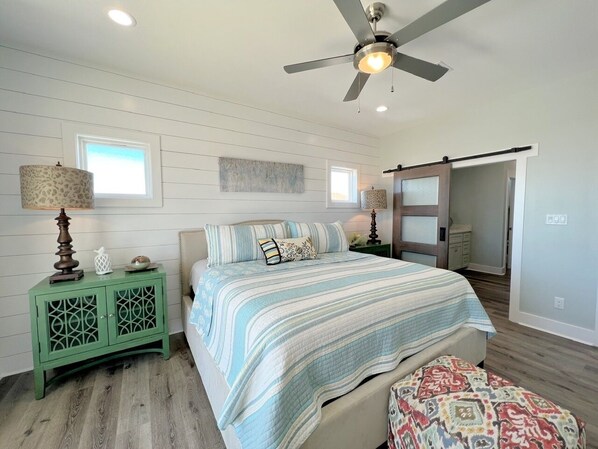 A bedroom with a bed, nightstands, a ceiling fan, and a sliding door. - Hooked On A Feeling 3 Bedroom Home by RedAwning (Port Bolivar)