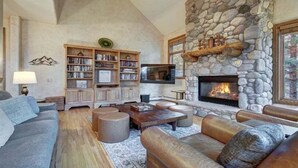 Una sala de estar acogedora con chimenea de piedra, una amplia estantería y asientos cómodos.