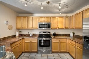 Kitchen features a central range, microwave, and stainless steel refrigerator.