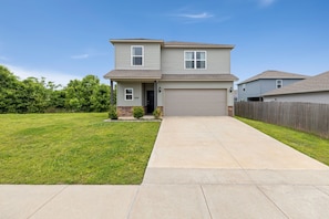 A two-story house with a garage, a front lawn, and a wooden fence.