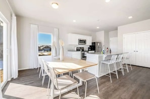 A modern kitchen with white cabinetry, a central island with seating, and a view to the outside.