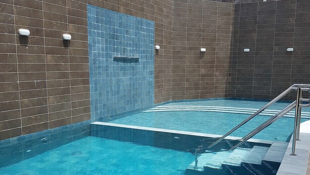 Une piscine avec un mur carrelé et un escalier en métal.