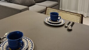Un salon moderne avec un canapé gris, une table basse sur laquelle se trouve une tasse et une soucoupe bleues, et un fauteuil décoratif.