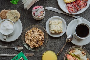 A breakfast setting with various food items and utensils on a table.