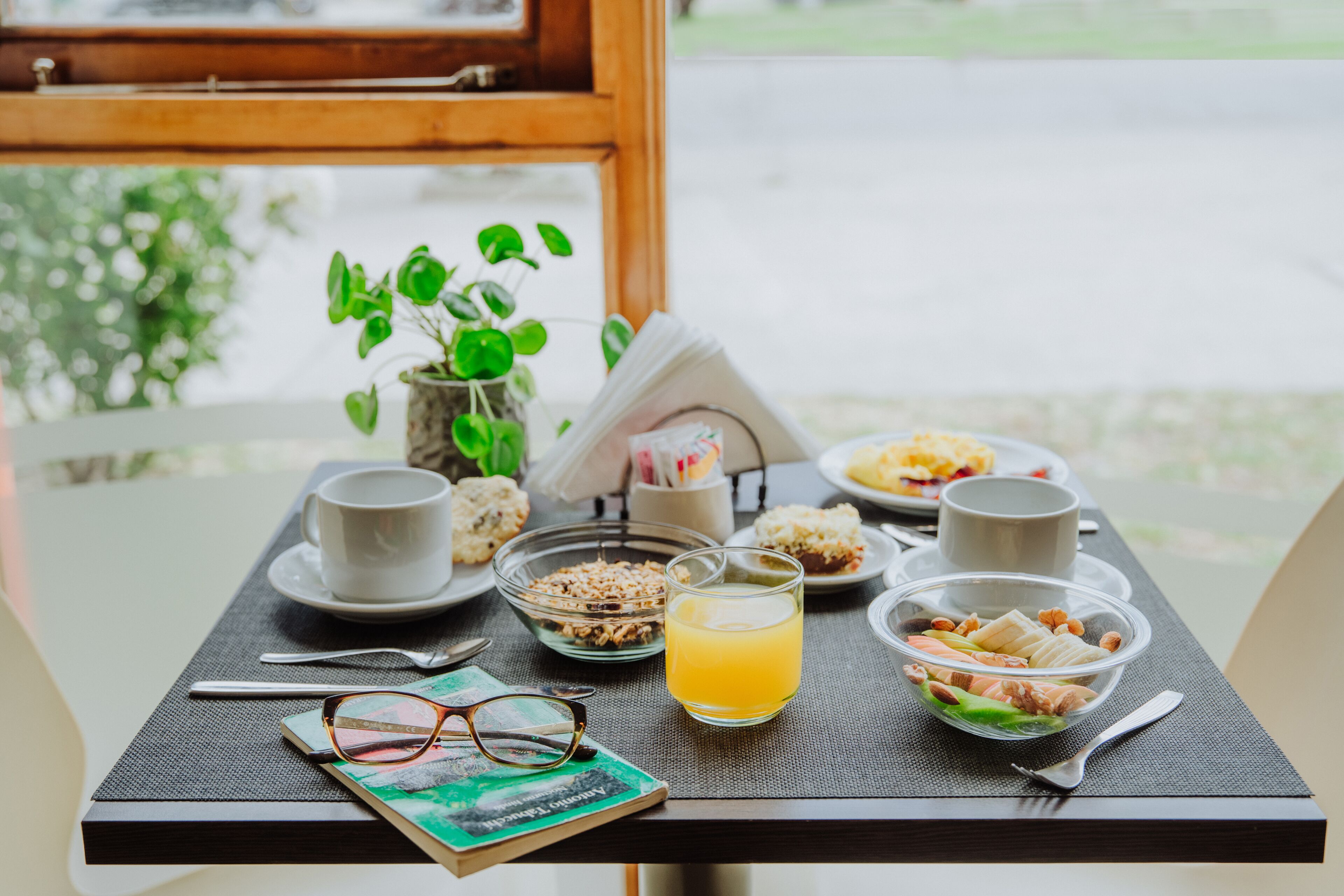A breakfast table with a cup, bowl, and book.