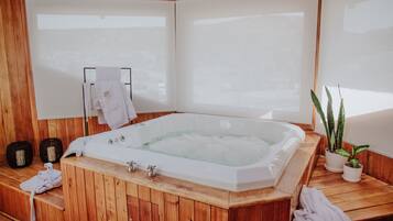 Eine Holzsauna mit einer großen Badewanne, Handtüchern und Topfpflanzen.