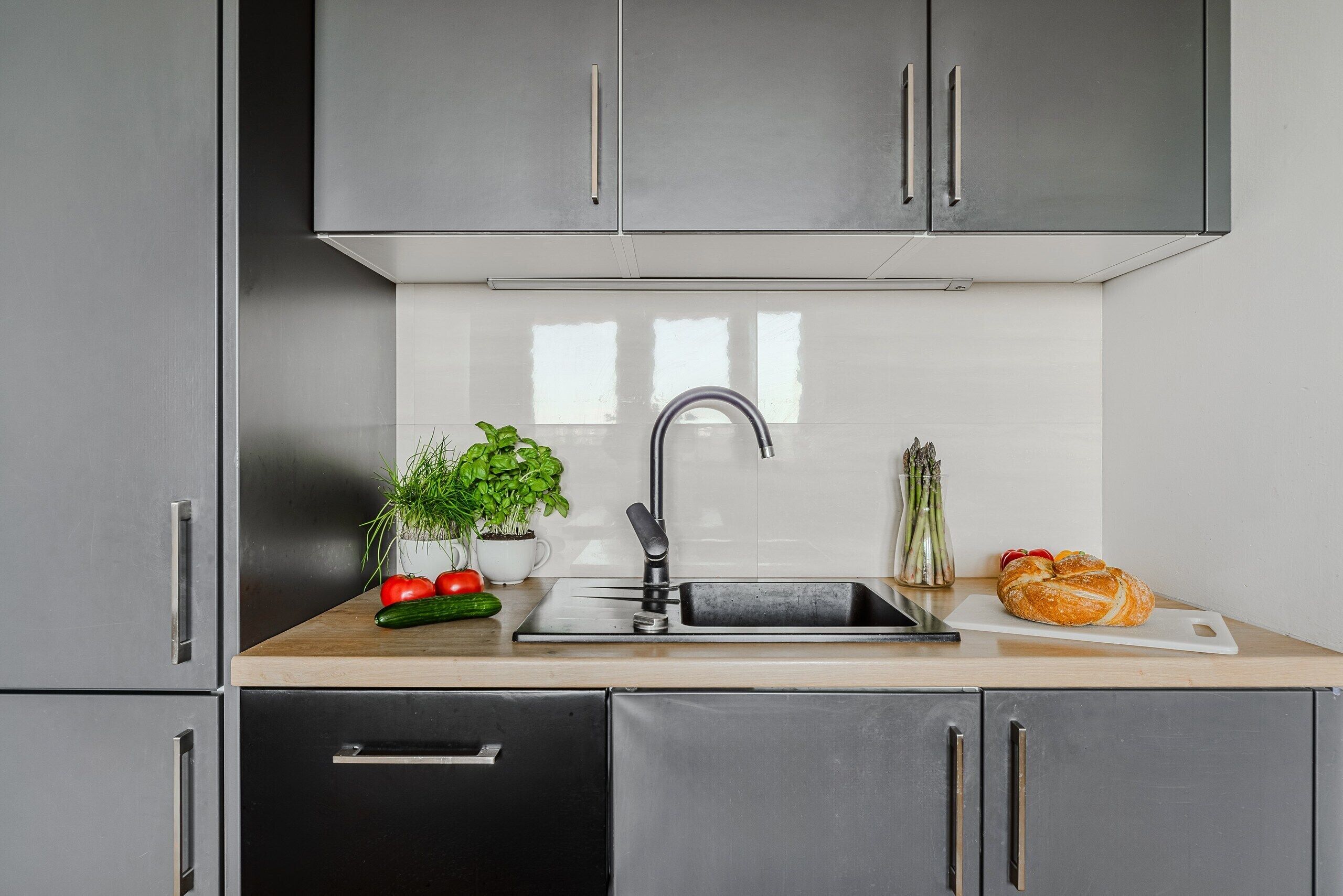 Una cocina moderna con gabinetes de acero inoxidable, un lavamanos y una encimera de madera.